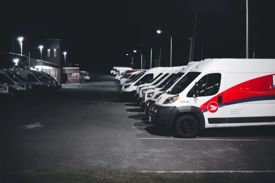 A fleet of patrol vans parked under floodlights at night